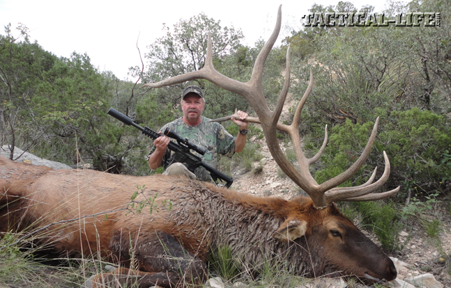 Bill Wilson, owner and founder of Wilson Combat, kneels behind his giant 6x6 trophy bull.