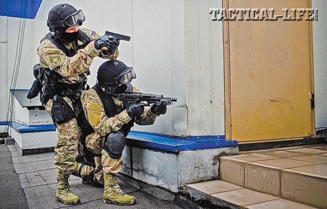 Two OMOH operators prepared for entry. They are armed with a Glock pistol and what appears to be an SR-2 submachine gun.