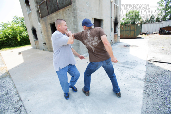 Use your right hand to slap his left hand across to your left.