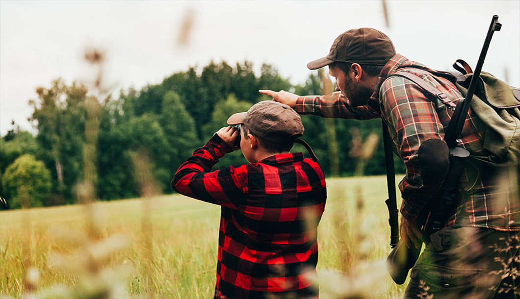 A father and son scout for deer on a weekend hunting trip.