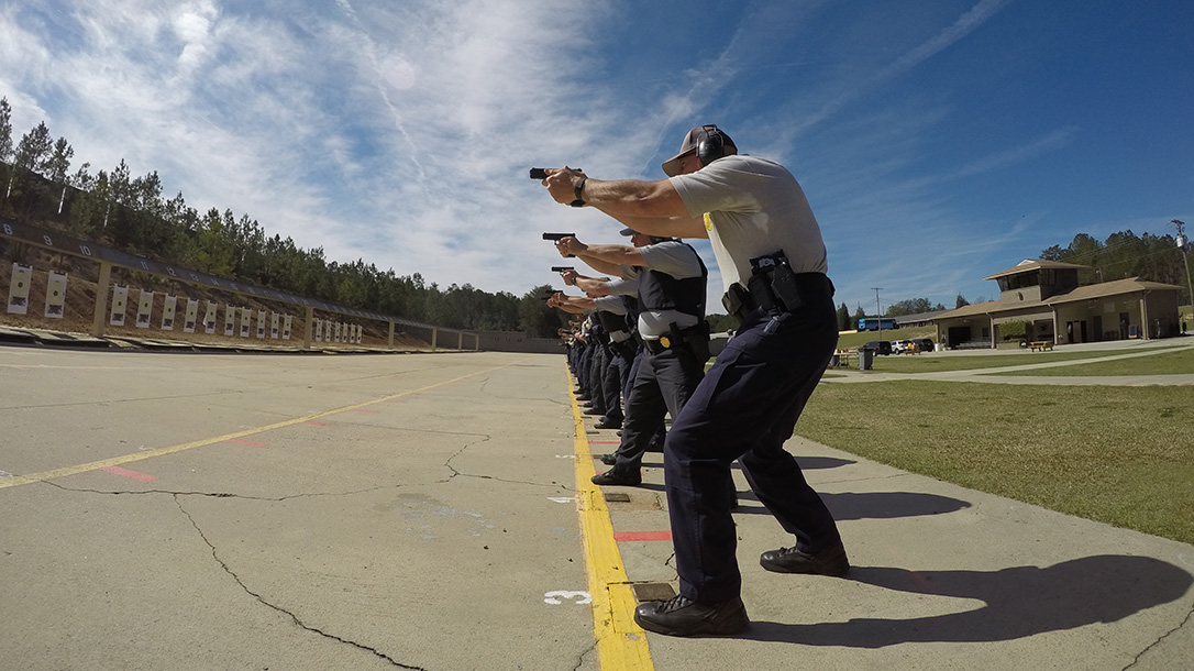A group of law enforcement professionals train with pistols on the range.