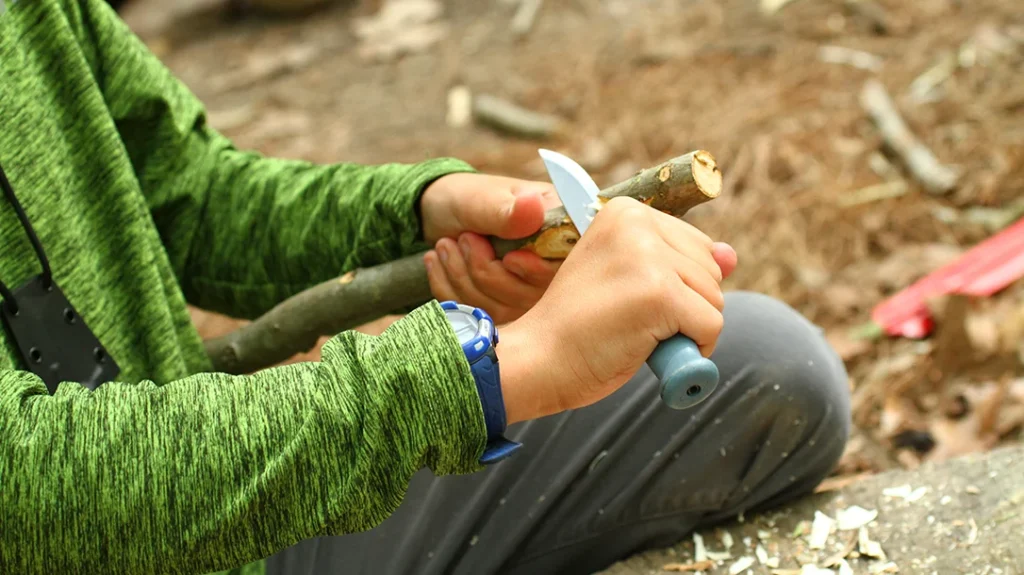 Knife Safety for Kids: An excellent example of a forehand/fist grip making a pot hook notch. The project is kept up and away from vital organs and arteries.