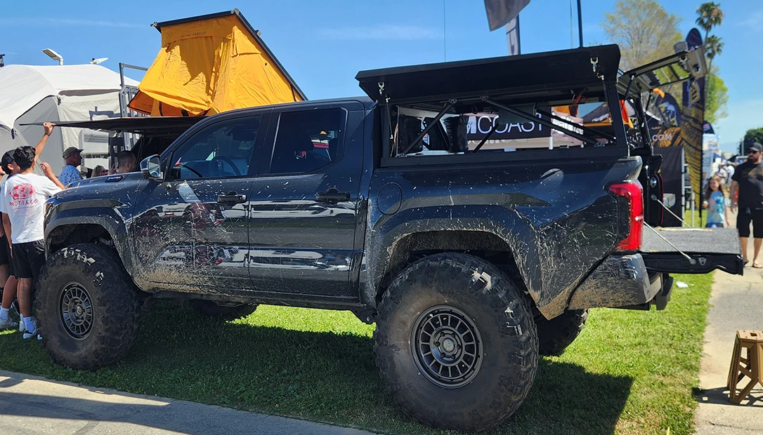 Adventure-ready overland vehicle parked beside camping accessories and gear
