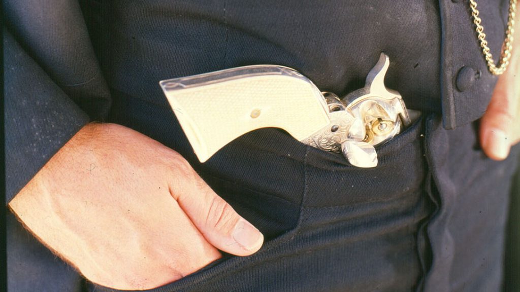 Without a belt and holster, a Colt Peacemaker tucked in waistband.