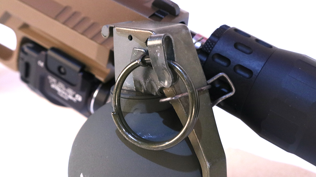 The removable wire safety clip retains the spoon in the closed potion. The safety ring must be rotated before it can be removed to arm the grenade.