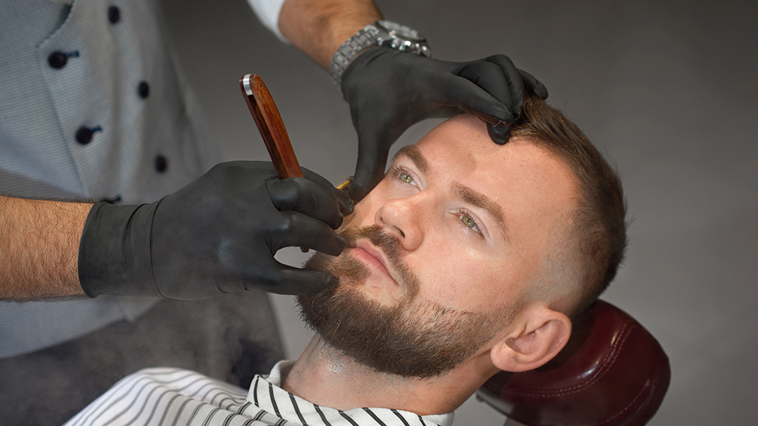 A man gets a straight razor shave from a qualified barber.