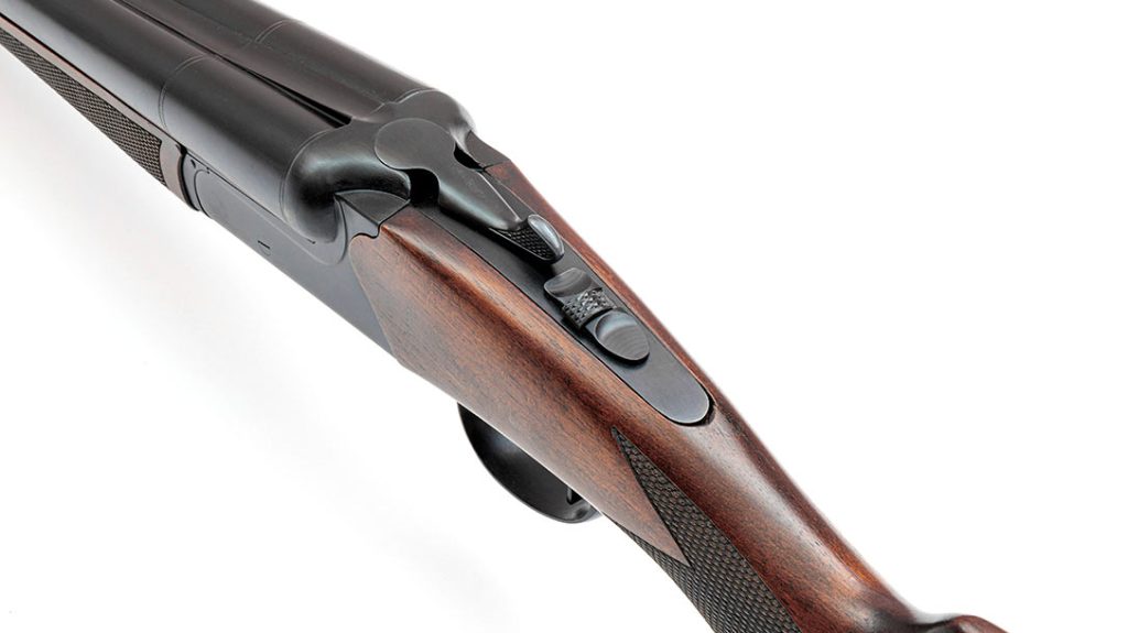 The top-lever behind the breech unlocks the shotgun for opening. Behind it, the safety is manually operated and also serves as a barrel selector switch.