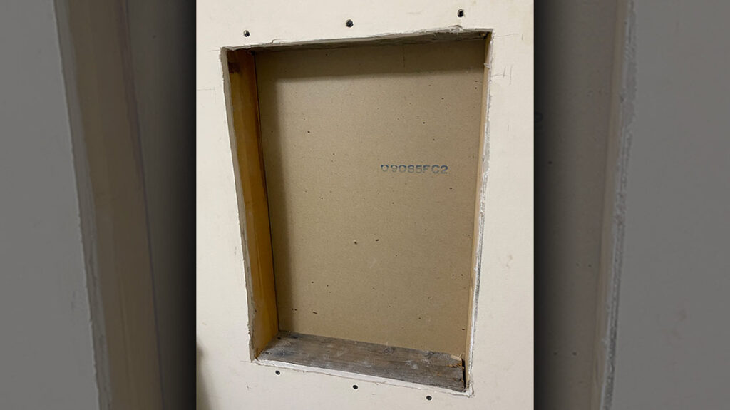 The finished Hornady Security SnapSafe In-Wall Safe mounting hole with 2 x 4 lumber headers and footers added to screw the wallboard too and support the safe body.