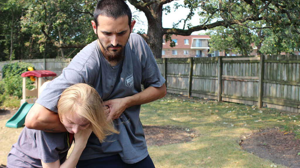 Combatives: a young girl prepares to defend against a headlock.